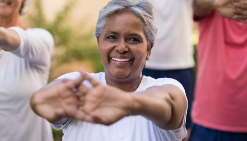 Portrait of senior woman stretching arms with friends